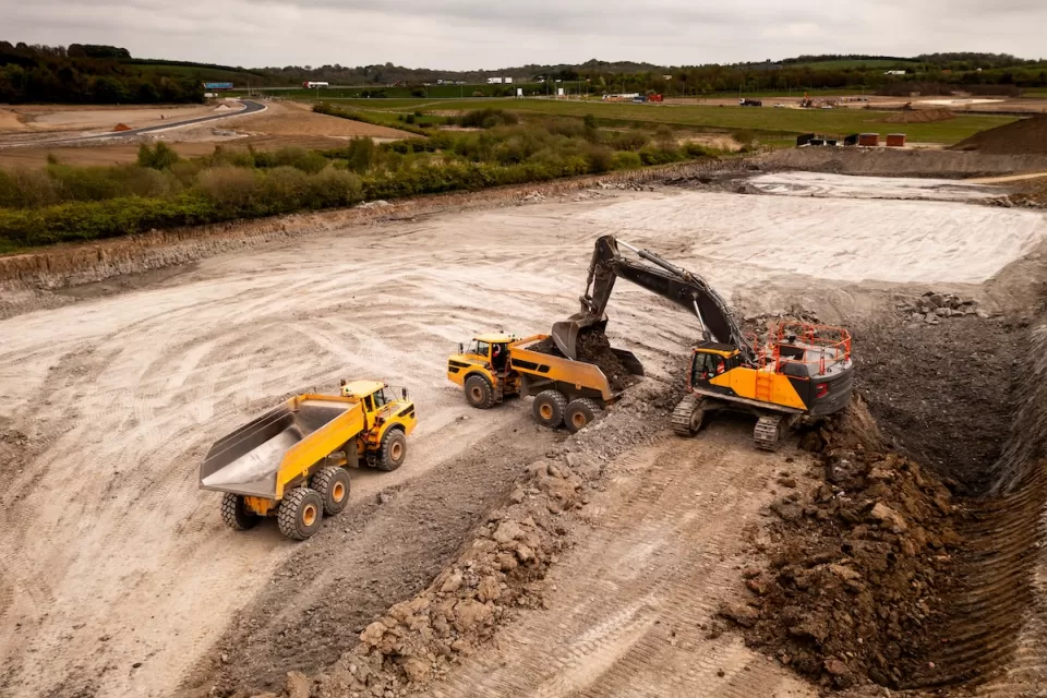 Aerial view of construction site with yellow dump truck and heavy machinery.